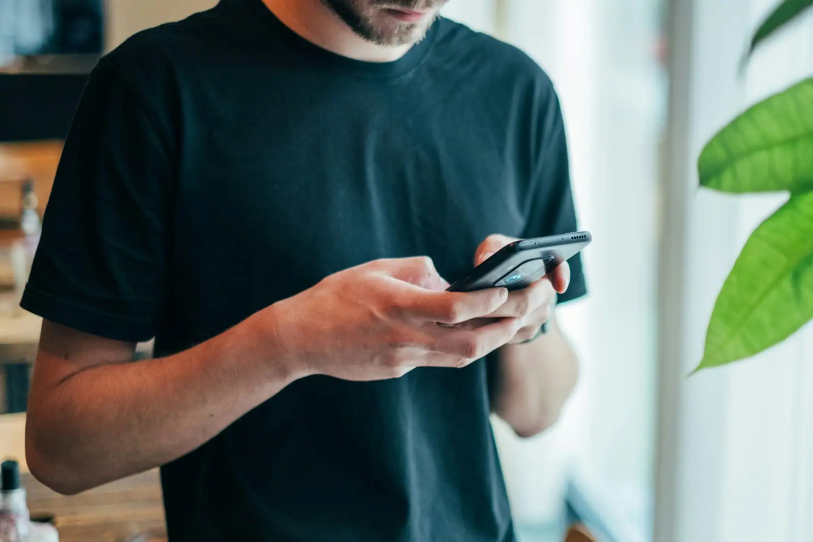 Vyras juodais marškinėliais rašo telefone